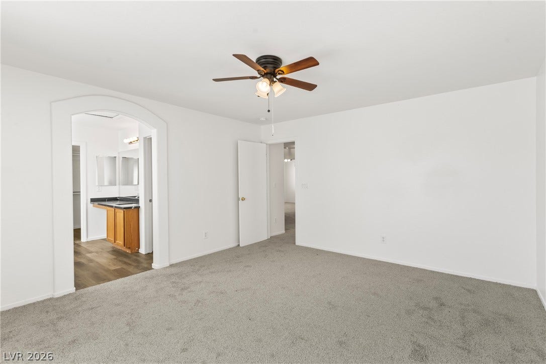 An arched doorway leads to the adjoining bathroom from this spacious bedroom.