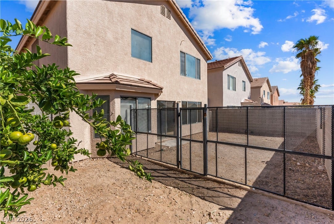 Secured fencing encloses the low-maintenance desert yard of this multi-level stucco home.