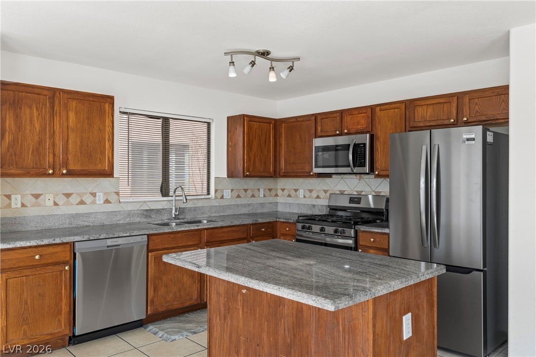 Rich wood cabinetry surrounds a central prep island topped with polished stone counters.