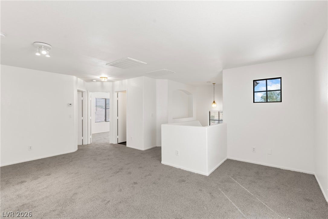 An open upstairs loft area features wall-to-wall carpeting and smooth plaster walls.