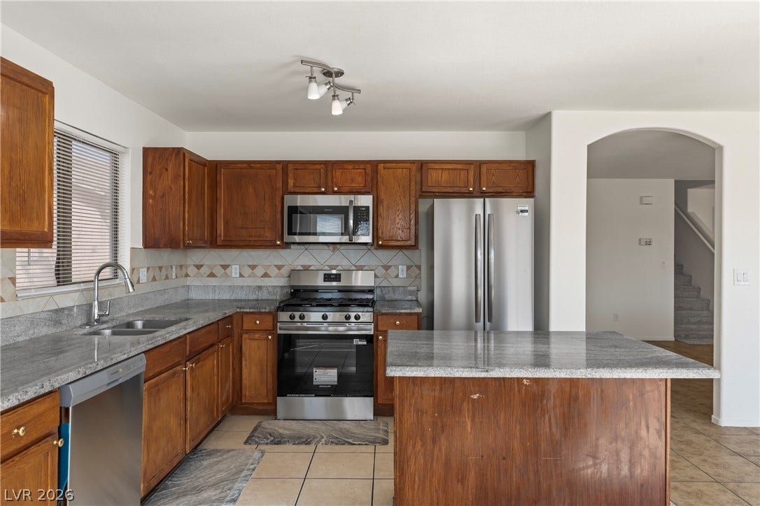 Rich wood cabinets and stone countertops flank a central island in this classic workspace.