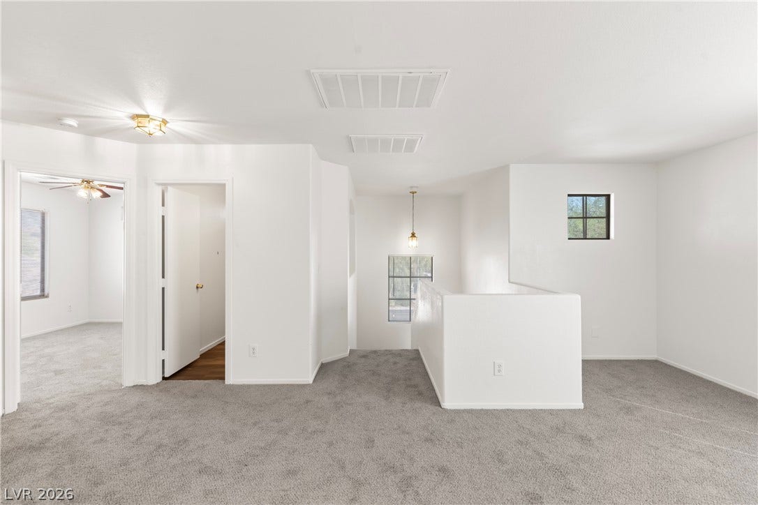 A spacious upper-level landing features soft wall-to-wall carpeting and neutral walls.