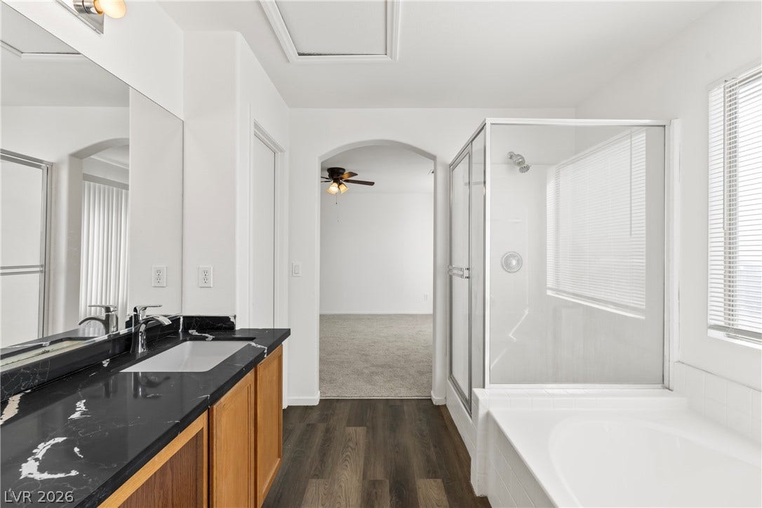 A glass-enclosed shower and adjacent soaking tub flank this modern bathroom layout.