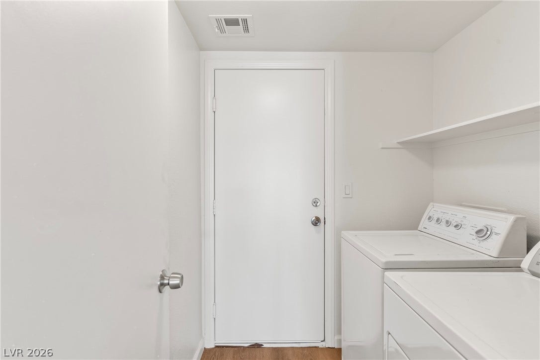 An organized laundry space incorporates functional built-in shelving alongside essential hookups.