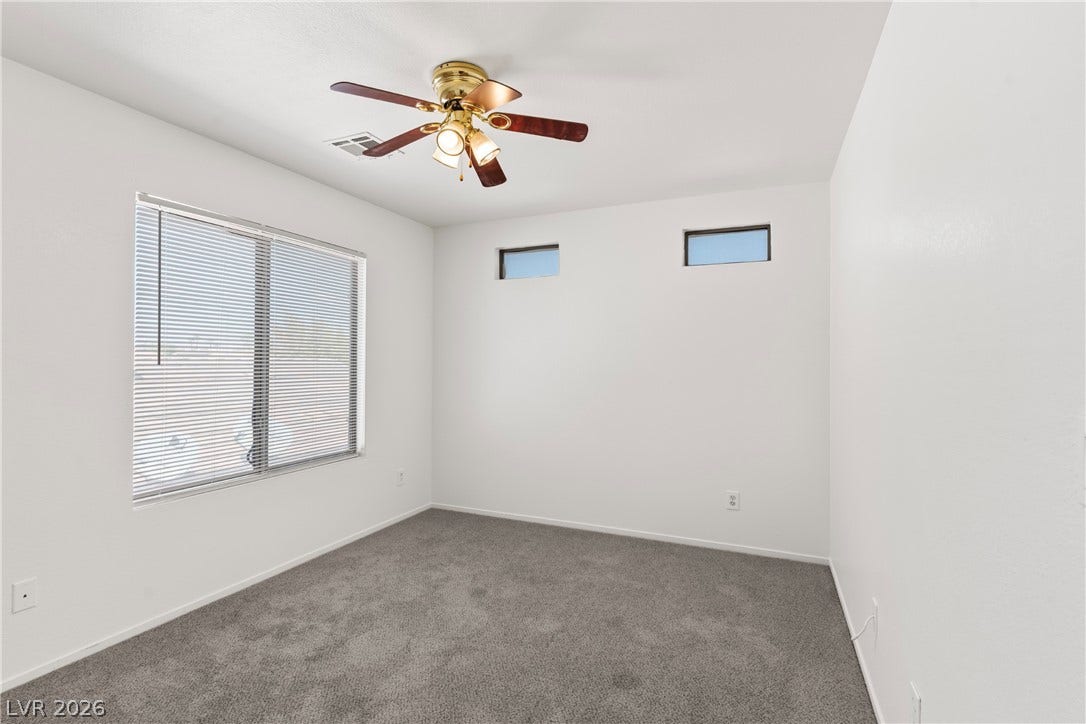 A spacious secondary bedroom features plush wall-to-wall carpeting and high clerestory windows.