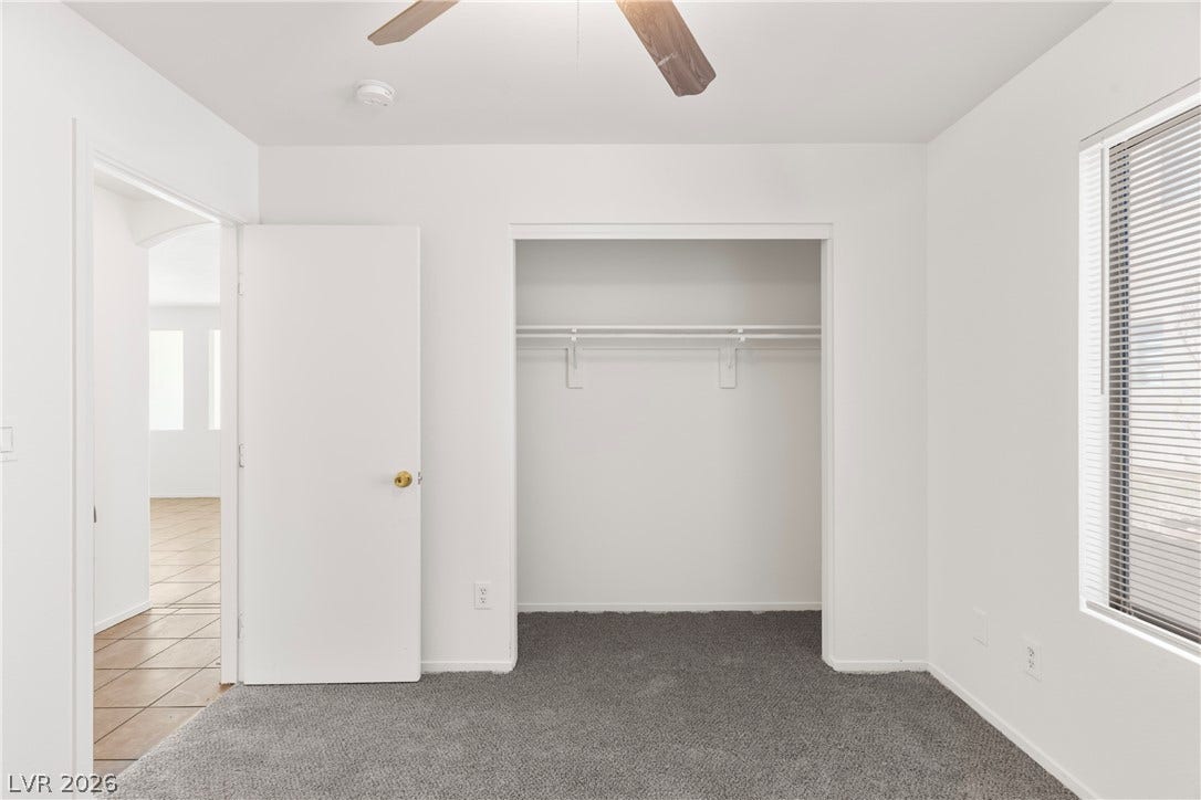 A secondary bedroom features clean plaster walls and wall-to-wall carpeting.