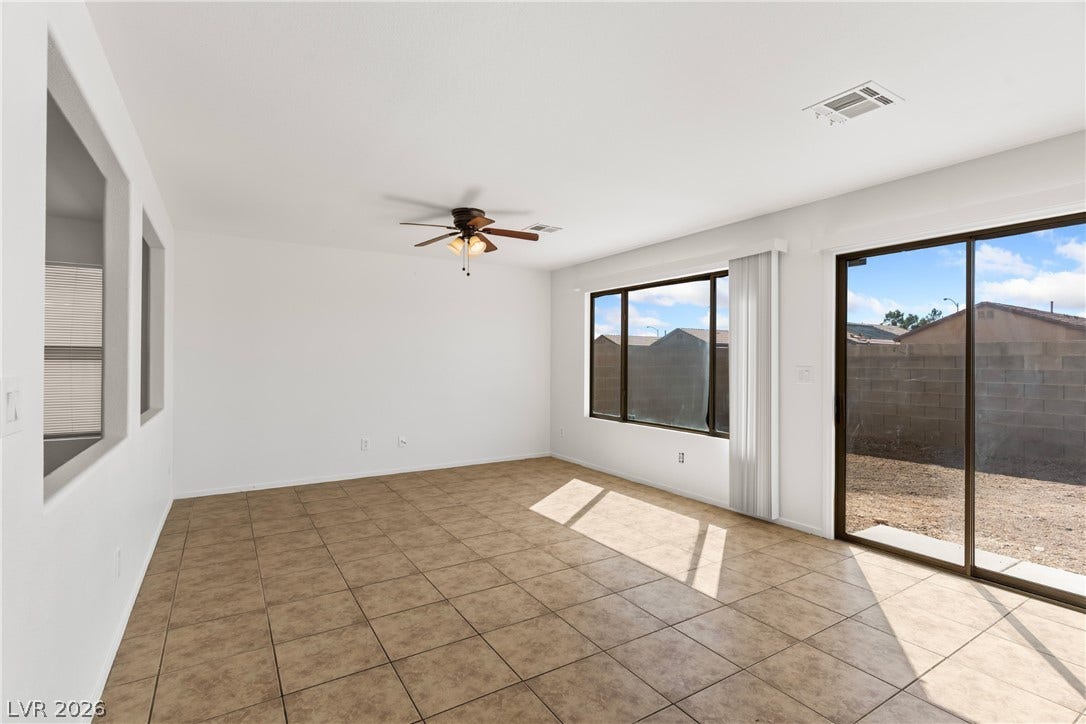 Sunlight streams across the tile flooring through sliding glass doors opening to the backyard.