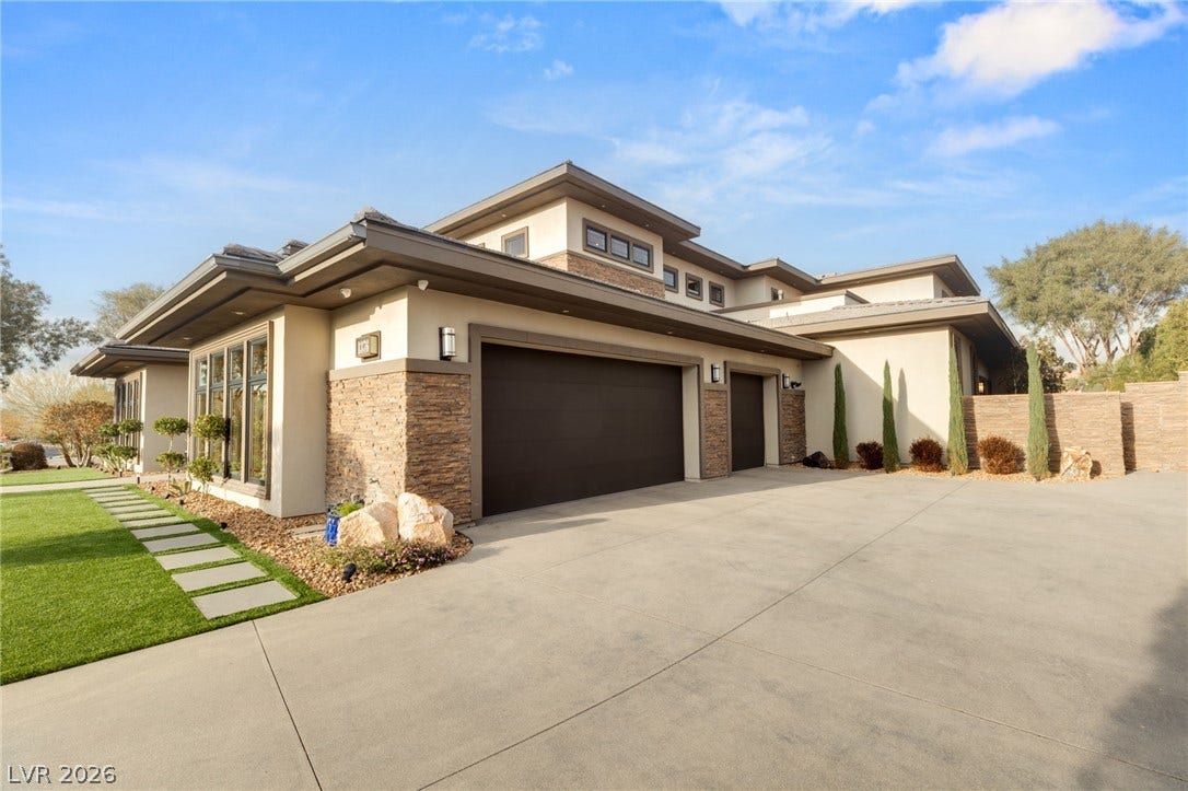 1376 Opal Valley Street, Henderson, NV 89052 An expansive concrete driveway leads to a modern multi-car garage with elegant stone accents.
