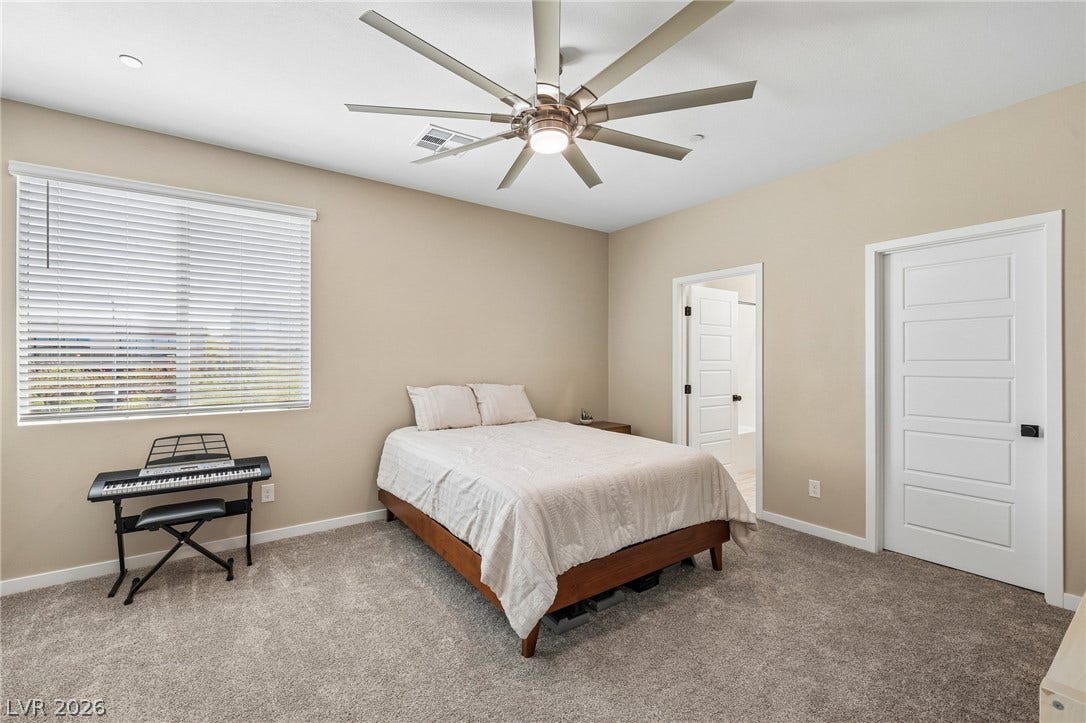 194 Viento Ridge Street, Henderson, NV 89012 An inviting bedroom space features plush carpeting and a large window offering natural light.