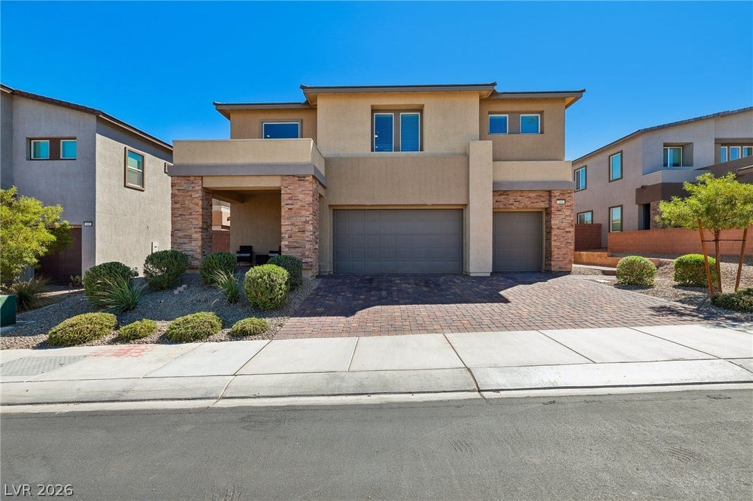194 Viento Ridge Street, Henderson, NV 89012 A striking modern facade pairs warm stucco with textured stone columns and a paved driveway.