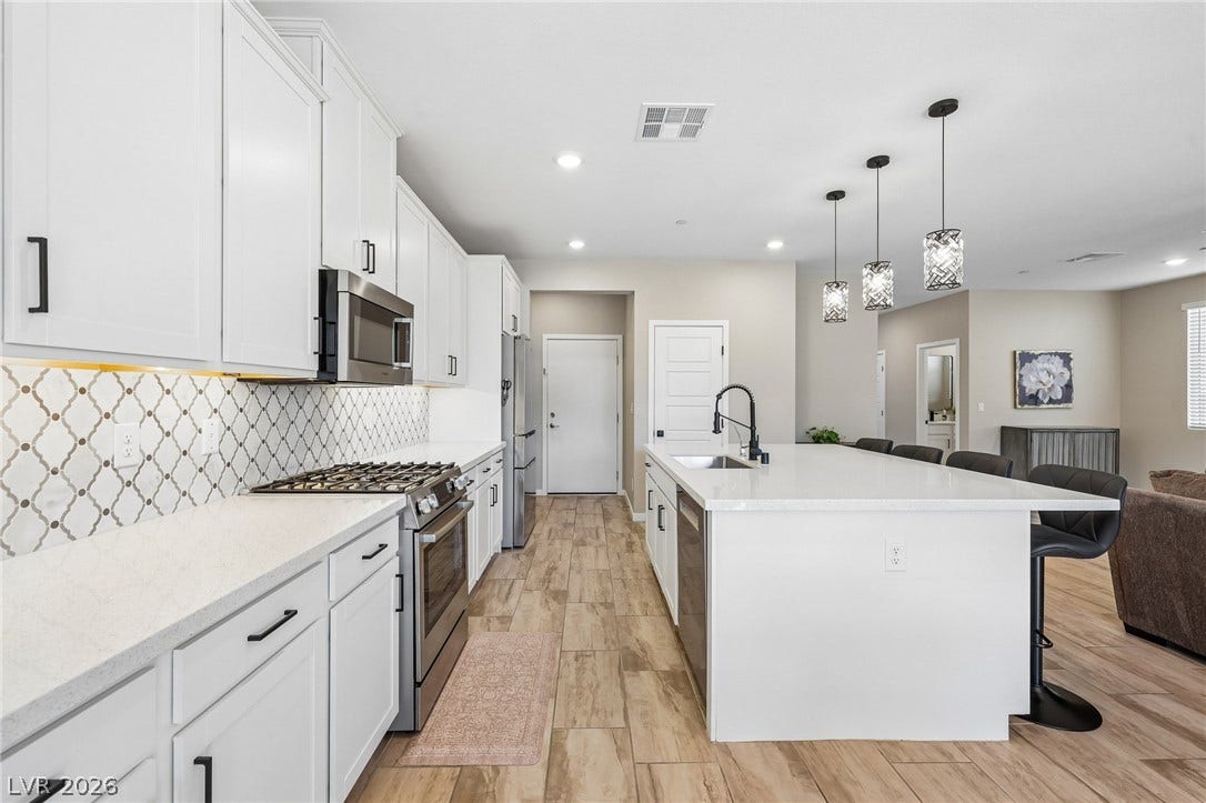 194 Viento Ridge Street, Henderson, NV 89012 Crisp white cabinetry paired with sleek countertops anchors this contemporary open-plan kitchen.
