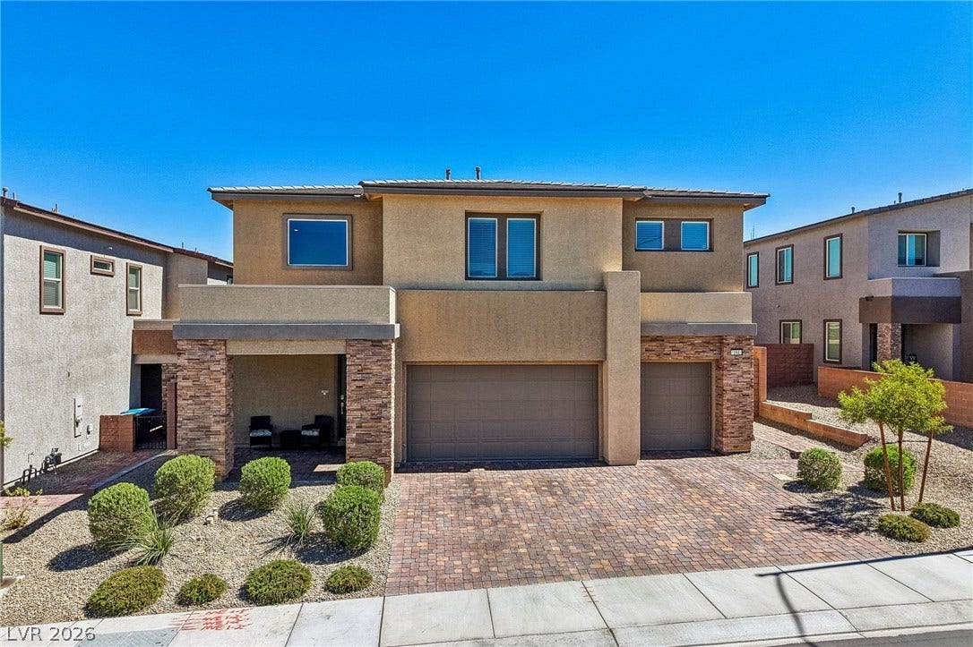194 Viento Ridge Street, Henderson, NV 89012 An inviting stone-accented facade showcases a spacious paver driveway under clear blue skies.