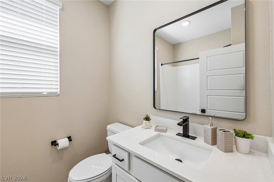 194 Viento Ridge Street, Henderson, NV 89012 A modern vanity with a sleek white countertop sits beneath a large rectangular mirror.