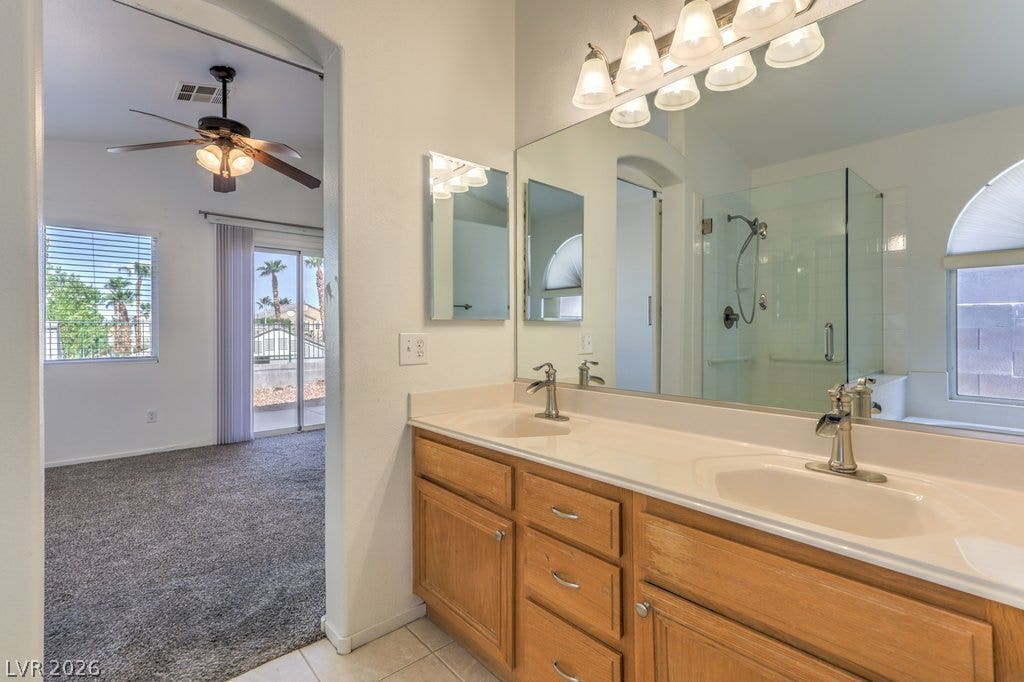 3186 CASTLE CANYON Avenue, Henderson, NV 89052 Double vanities and a glass-enclosed shower highlight this functional primary bathroom layout.