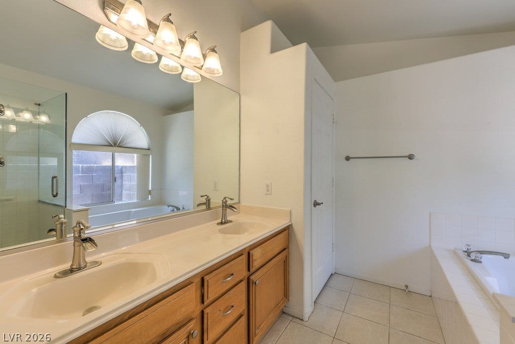 3186 CASTLE CANYON Avenue, Henderson, NV 89052 High ceilings and tiled flooring elevate this spacious primary bathroom featuring a double vanity.