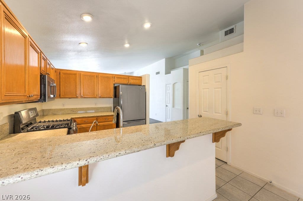 3186 CASTLE CANYON Avenue, Henderson, NV 89052 Rich oak cabinetry and durable granite countertops anchor this functional open kitchen space.