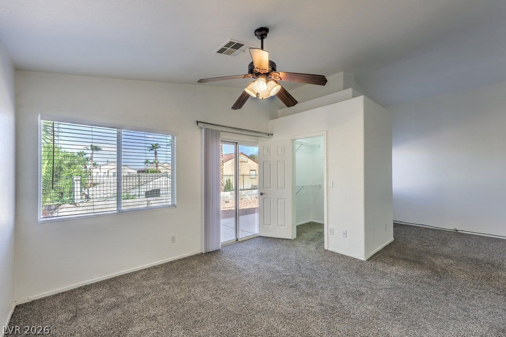 3186 CASTLE CANYON Avenue, Henderson, NV 89052 A spacious bedroom features plush carpeting, high ceilings, and sliding doors leading outside.