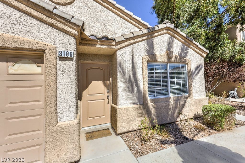 3186 CASTLE CANYON Avenue, Henderson, NV 89052 A welcoming concrete entryway leads past a classic stucco exterior under a tiled roofline.