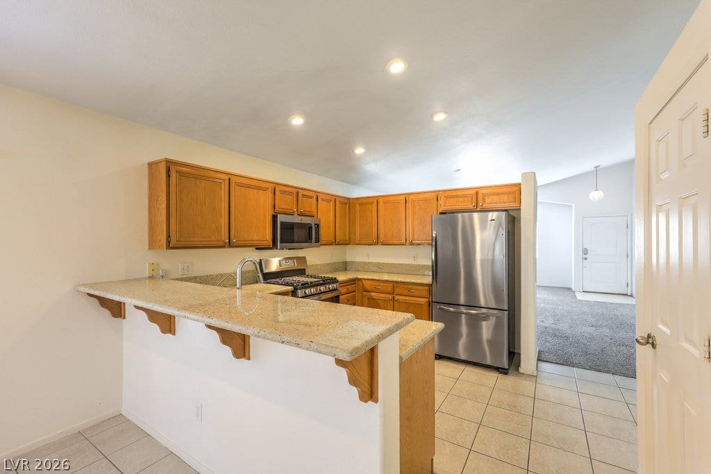3186 CASTLE CANYON Avenue, Henderson, NV 89052 An open kitchen layout features classic oak cabinetry and granite counters paired with tile floors.