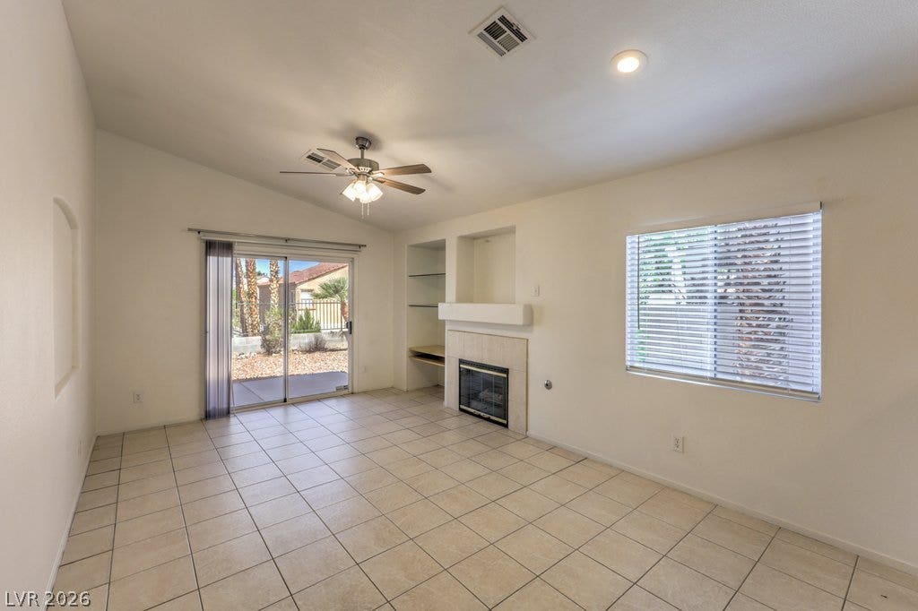 3186 CASTLE CANYON Avenue, Henderson, NV 89052 Sliding glass doors open to the outdoors from this tiled living space with a fireplace.