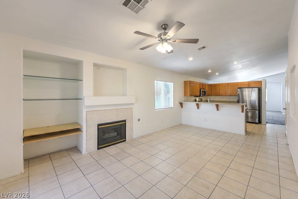 3186 CASTLE CANYON Avenue, Henderson, NV 89052 Tiled flooring flows through an open-concept living area anchored by a classic fireplace.