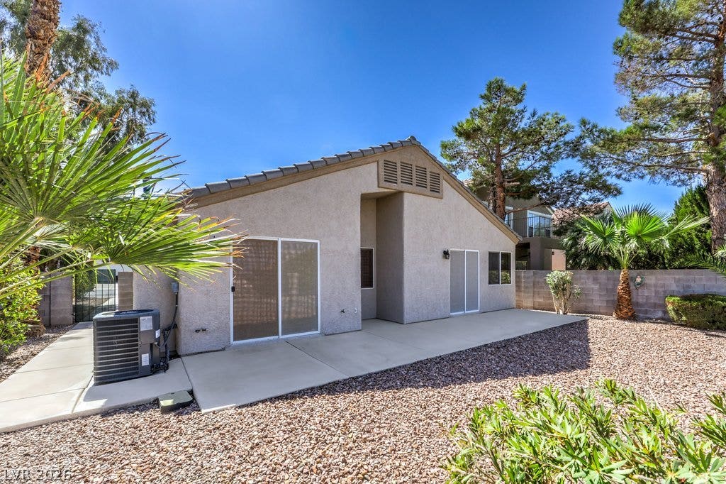 3186 CASTLE CANYON Avenue, Henderson, NV 89052 Sliding glass doors open onto a concrete patio surrounded by desert-inspired landscaping.