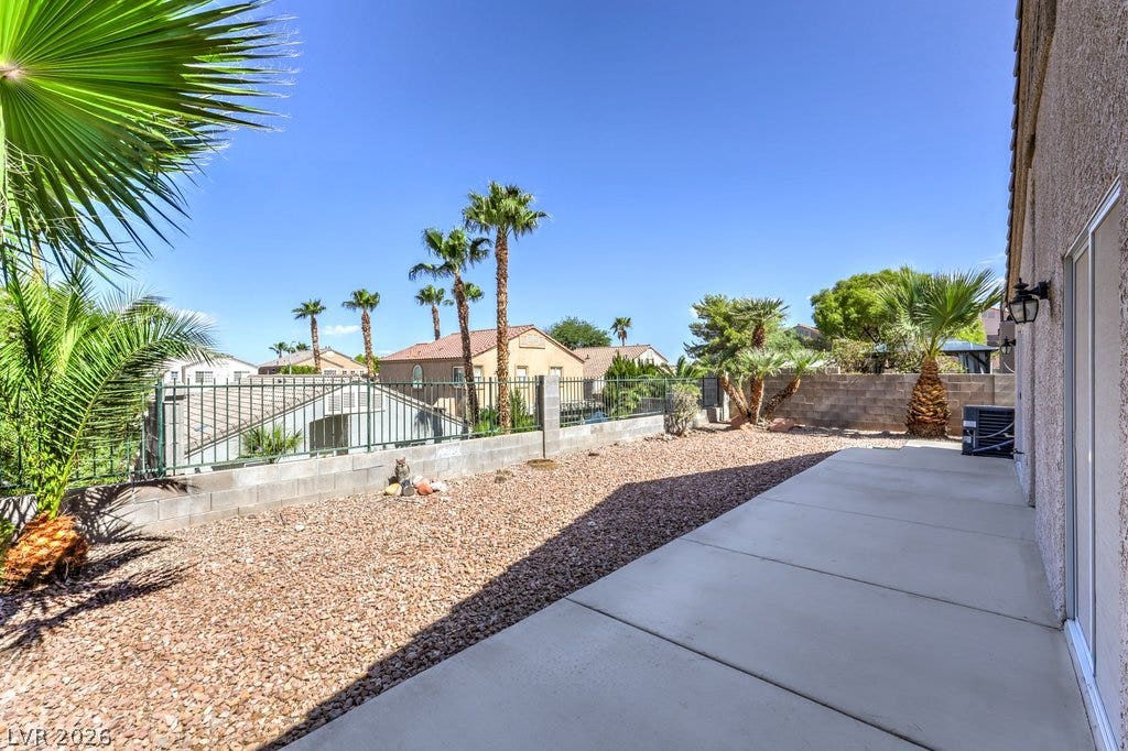 3186 CASTLE CANYON Avenue, Henderson, NV 89052 A low-maintenance concrete patio borders a gravel yard framed by block fencing and palm trees.