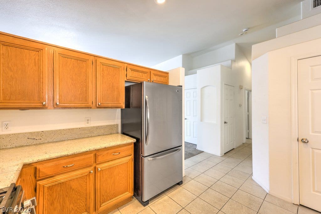 3186 CASTLE CANYON Avenue, Henderson, NV 89052 Warm oak cabinetry pairs with stone countertops in this functional kitchen layout.