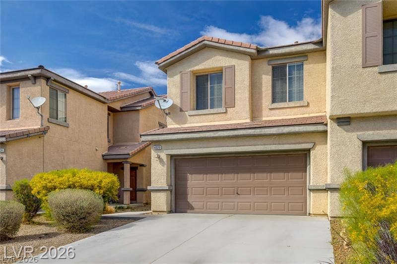 4020 Thomas Patrick Avenue, North Las Vegas, NV 89032 Desert landscaping and a concrete driveway lead to the attached garage of this multi-level stucco home.
