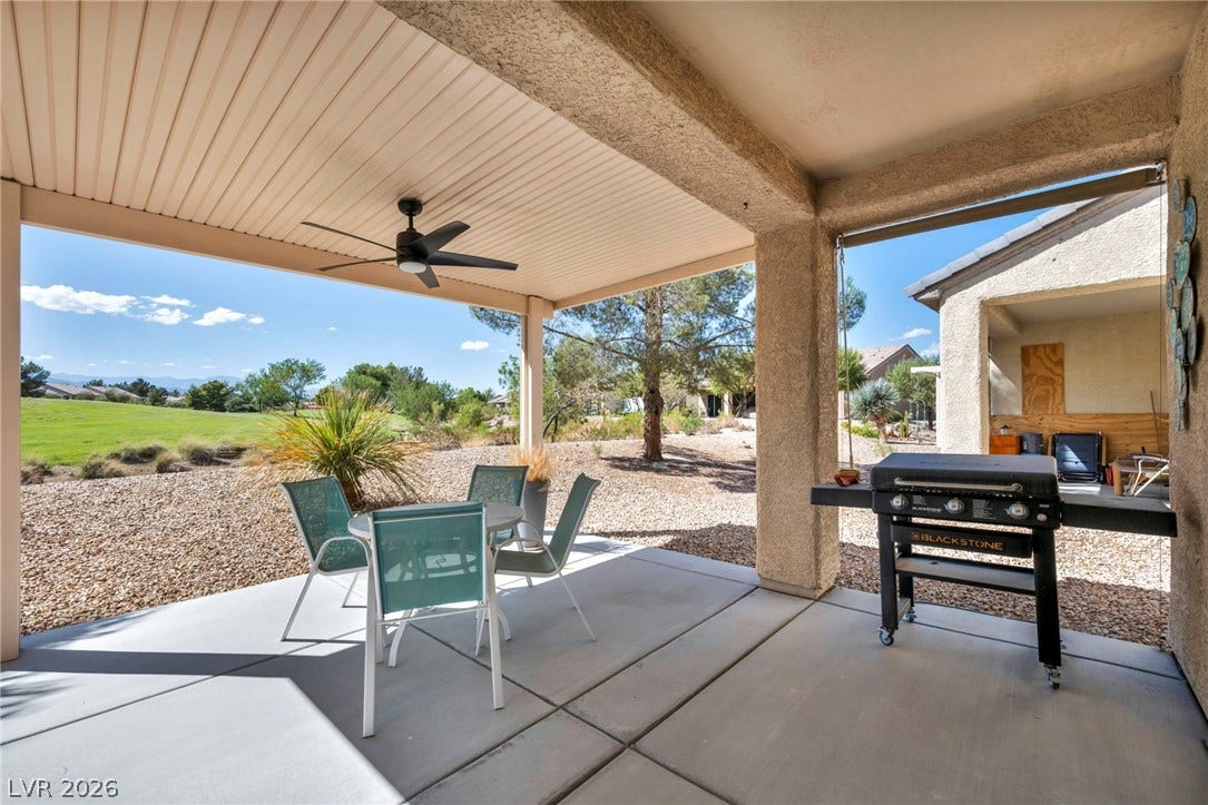 Shaded concrete patio looks out onto a low-maintenance gravel yard bordering scenic green space.