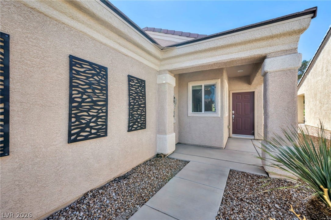 Concrete columns frame a sheltered entryway leading to the front door of this stucco home.