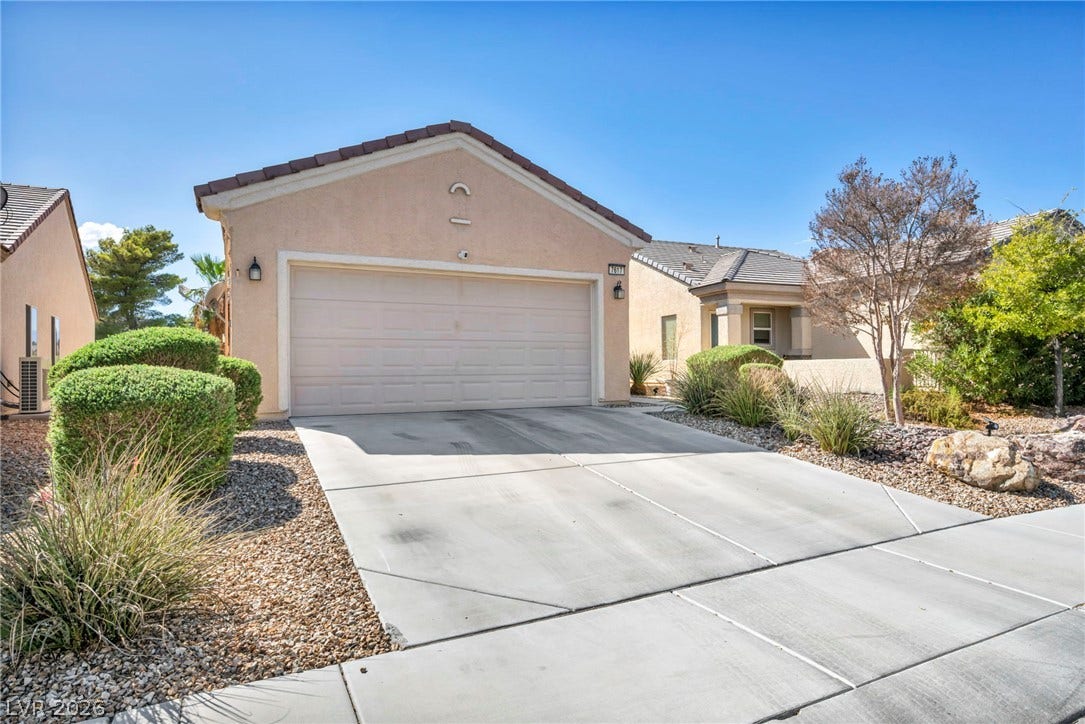 A spacious concrete driveway leads to a classic stucco exterior with tile roofing.