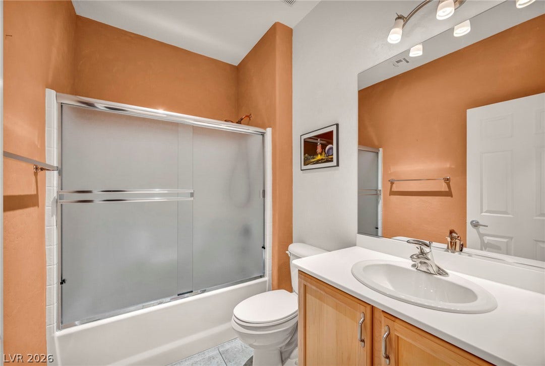 Warm earth tones accent this bathroom featuring a single vanity and a tub-shower combination.