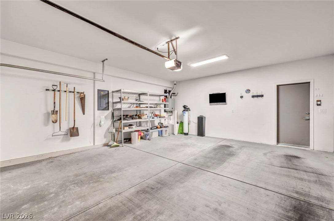 A spacious garage features durable concrete flooring and high ceilings.