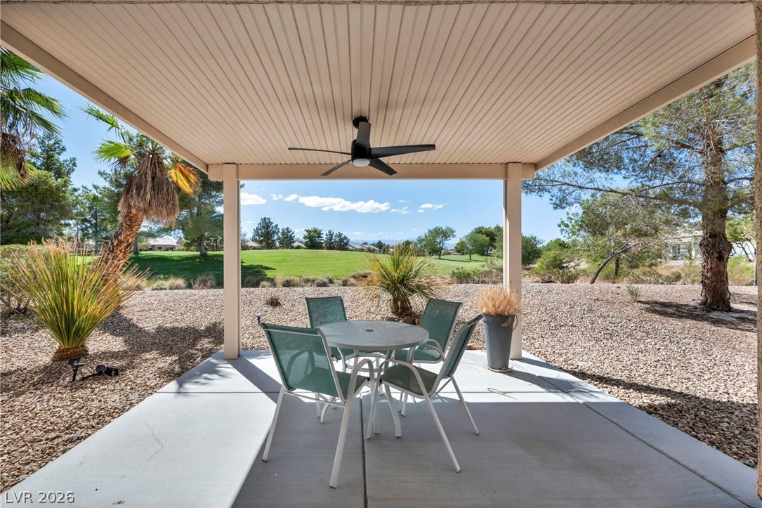 Shaded concrete patio overlooks a rolling green golf course under clear blue skies.
