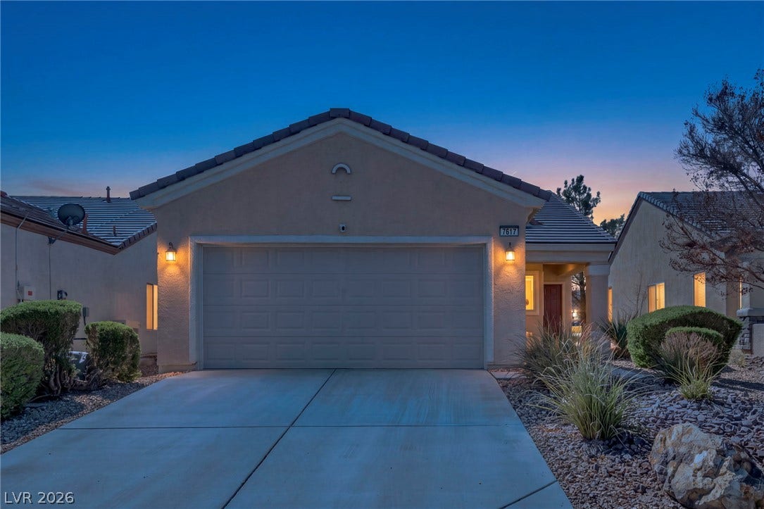 A spacious driveway leads directly to a neat attached two-car garage under a tiled roof.