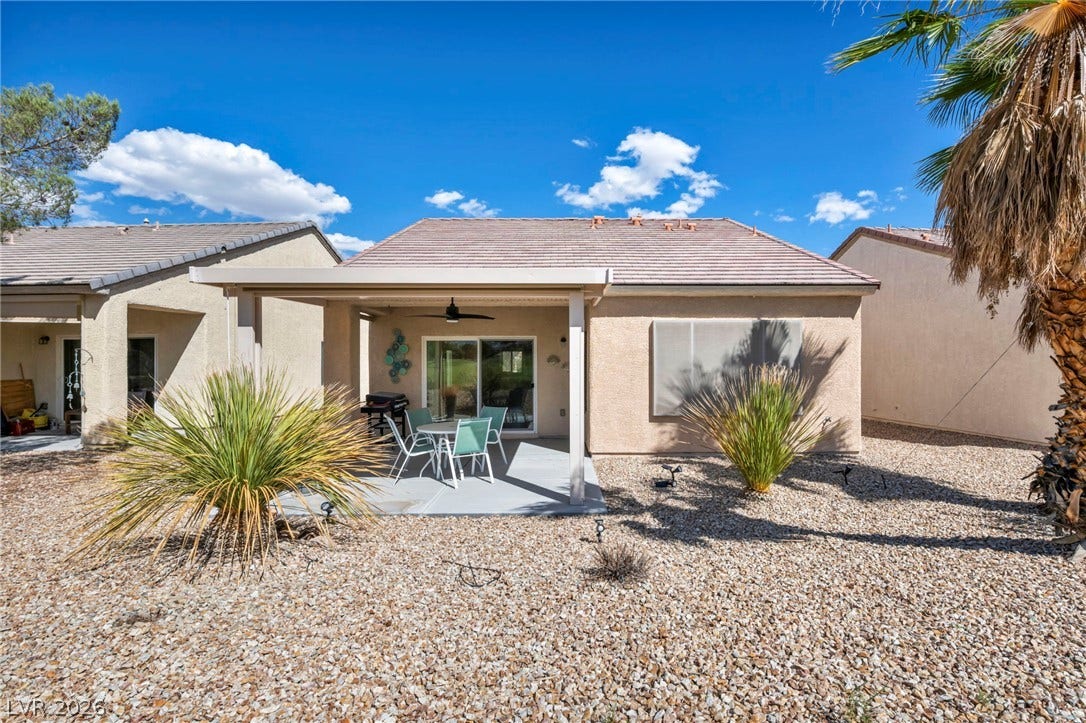 An inviting covered patio overlooks the low-maintenance desert landscaping under clear blue skies.