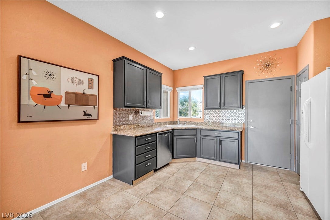 Dark cabinetry and granite countertops frame a corner sink layout beneath recessed lighting.