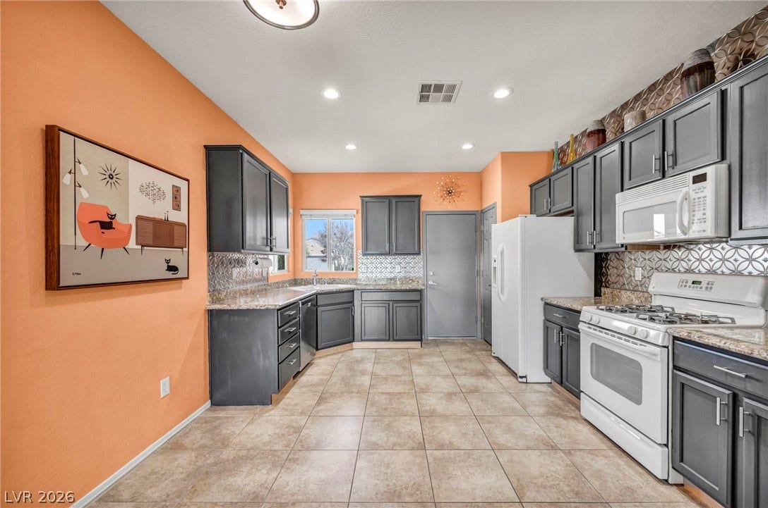 A spacious kitchen features tile flooring and abundant dark cabinetry paired with granite countertops.