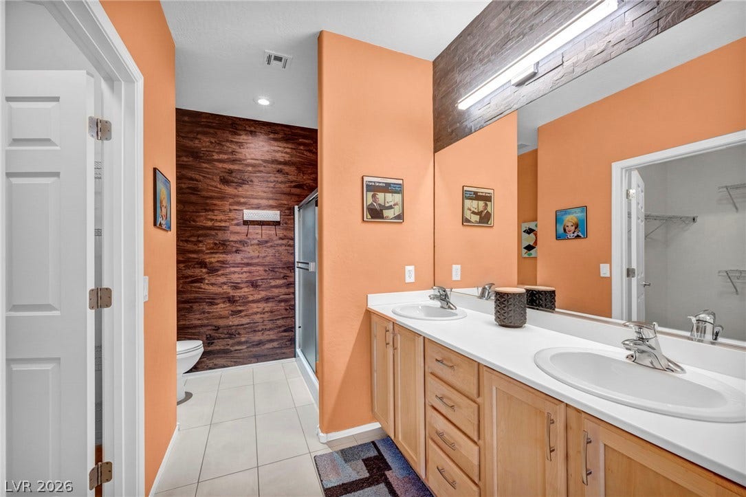 Stone counters and custom wall paneling bring distinct character to this spacious vanity area.