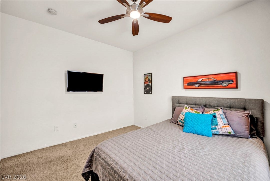Plush wall-to-wall carpeting and clean white walls define this comfortable bedroom space.