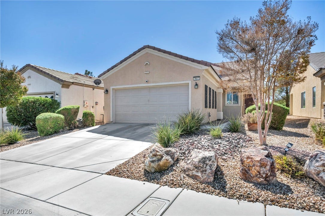 Low-maintenance desert landscaping frames the front of this stucco home featuring a two-car garage.