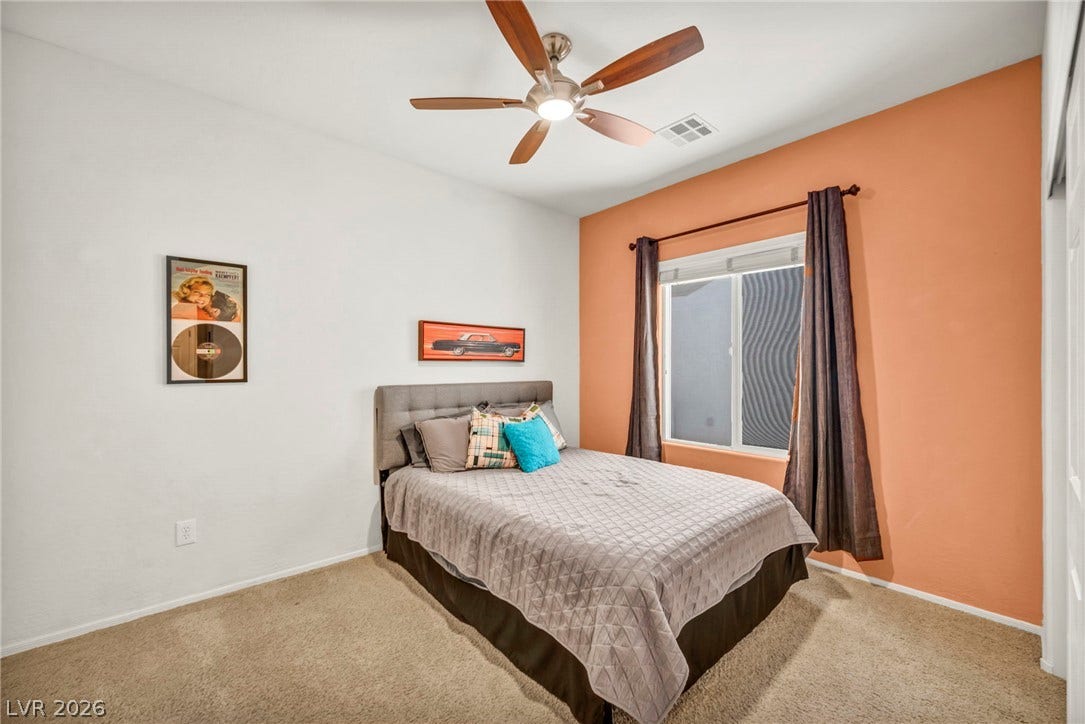 Natural light streams through a large window, highlighting the carpeted flooring and neutral walls.