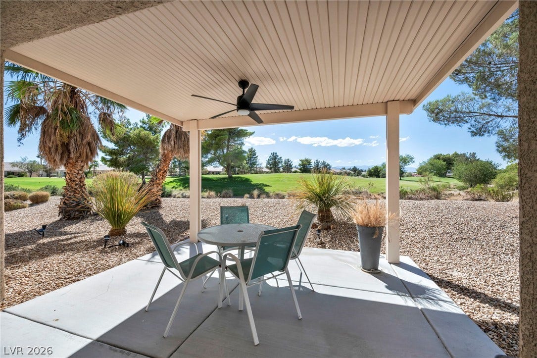 An inviting covered concrete patio looks out onto a serene, manicured golf course landscape.