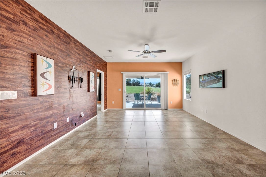 Sliding glass doors open from this versatile tiled living space to the rear patio.