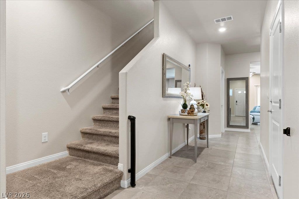 A well-lit entry hall with tile flooring and a carpeted staircase invites upward to additional levels.
