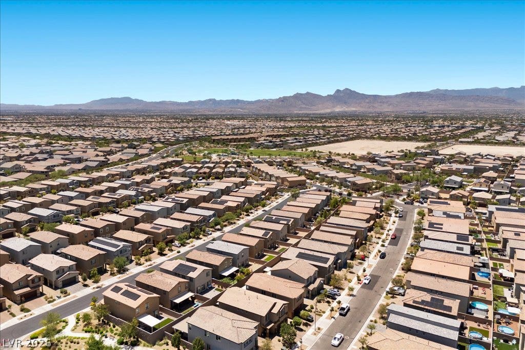 An aerial perspective reveals a vast neighborhood of homes against a backdrop of distant mountains.