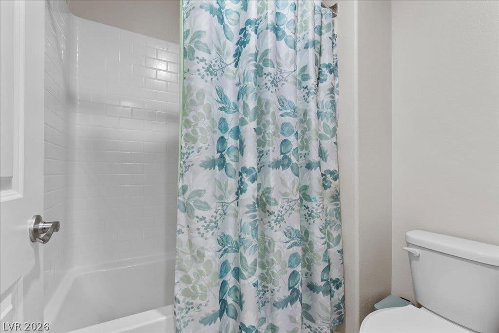 A well-maintained tub-shower combination features subway tile surround and a decorative curtain.