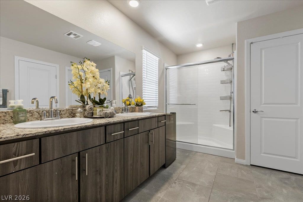 A well-appointed bathroom features a double vanity with granite counters and a spacious walk-in shower.