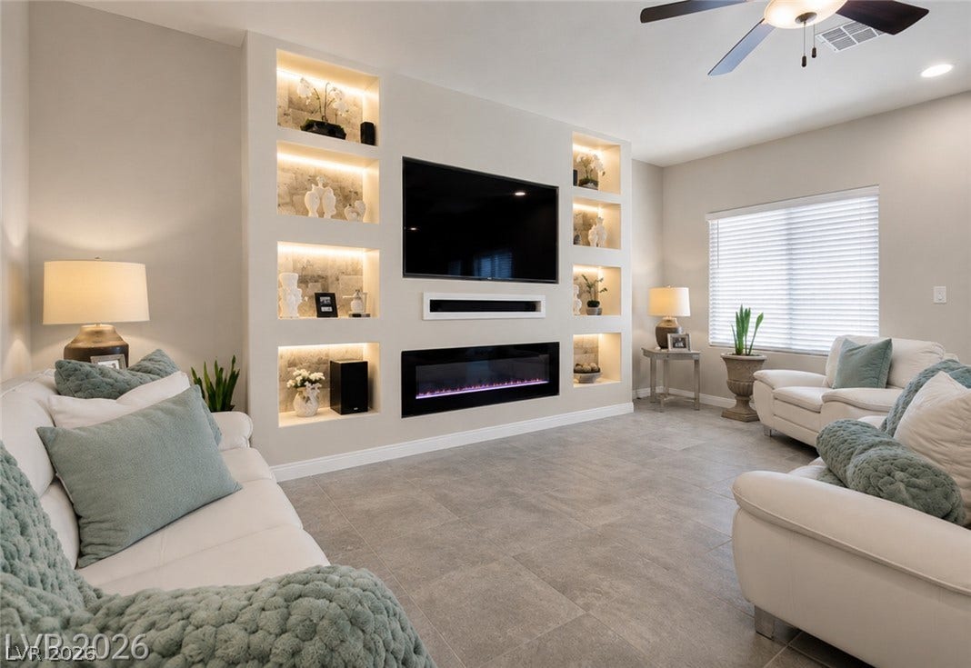 An inviting family room offers a recessed wall unit, featuring built-in shelving with ambient lighting and an electric fireplace.